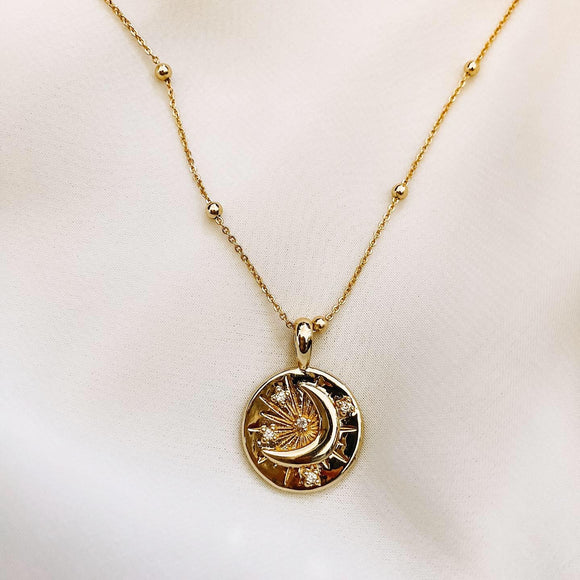 Gold moon charm on gold ball necklace with white background